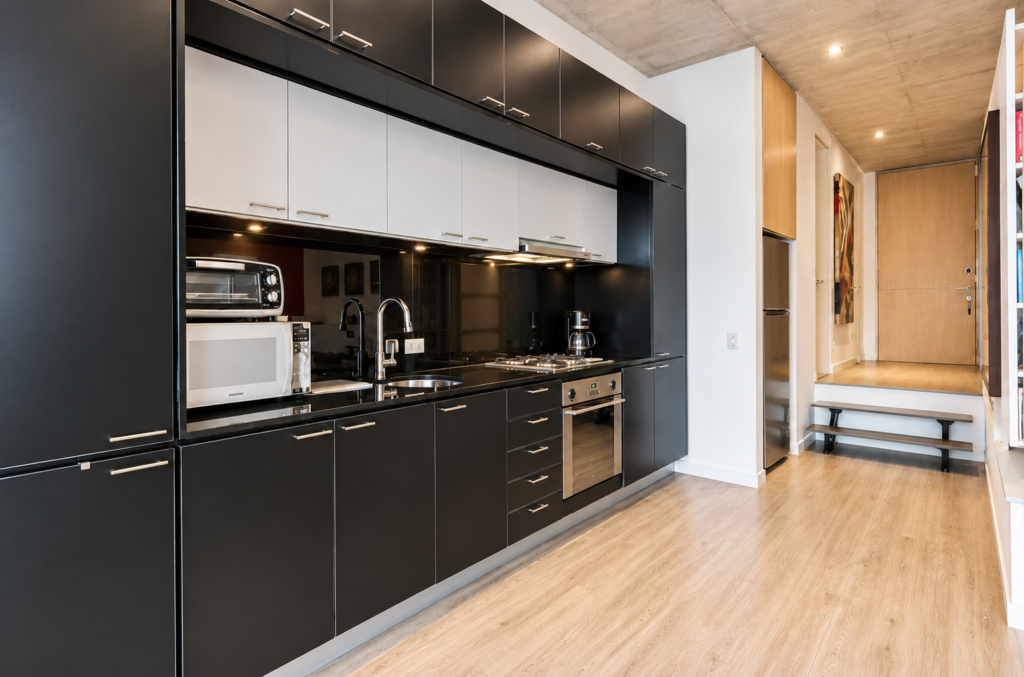 Cocina en tono oscuro con frentes lisos y torre de hornos